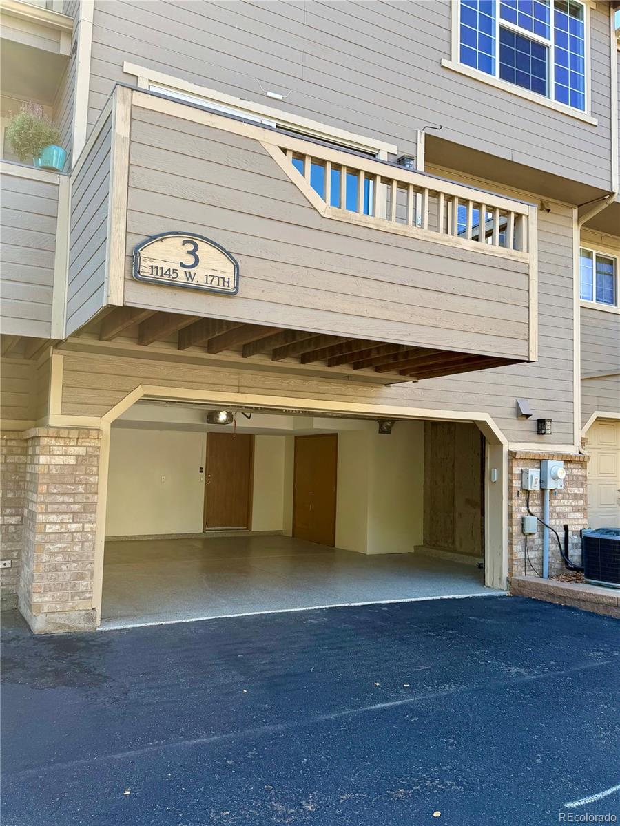 Residential building exterior with a numbered balcony above an open garage.