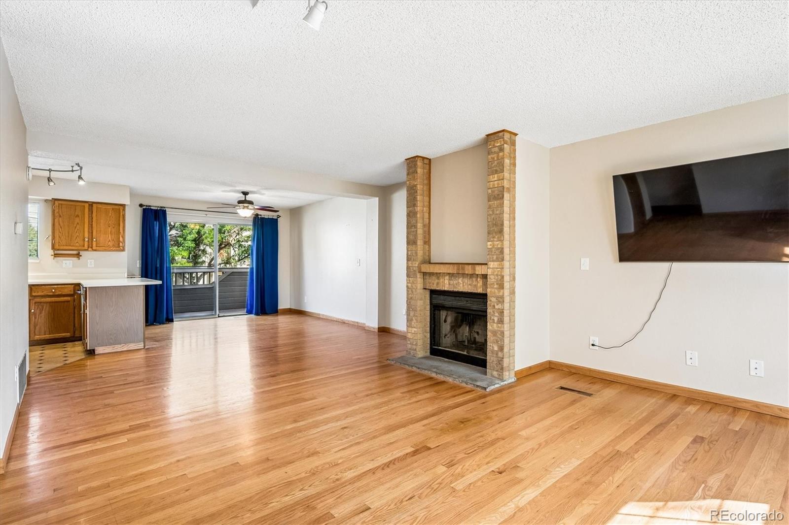 Open living area with hardwood floors, brick fireplace, and sliding doors to a balcony.