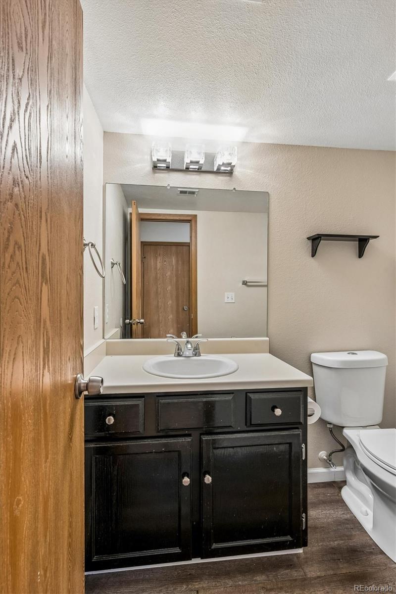 Bathroom with dark wood vanity, oval sink, large mirror, and wood-look flooring.