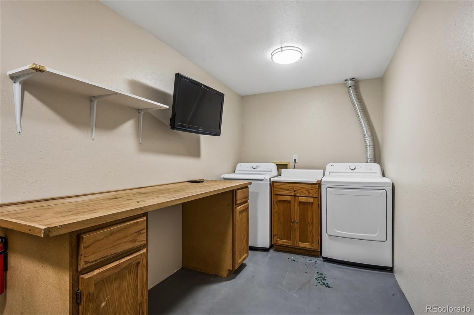 Laundry room with washer, dryer, and long wooden workbench with cabinets.