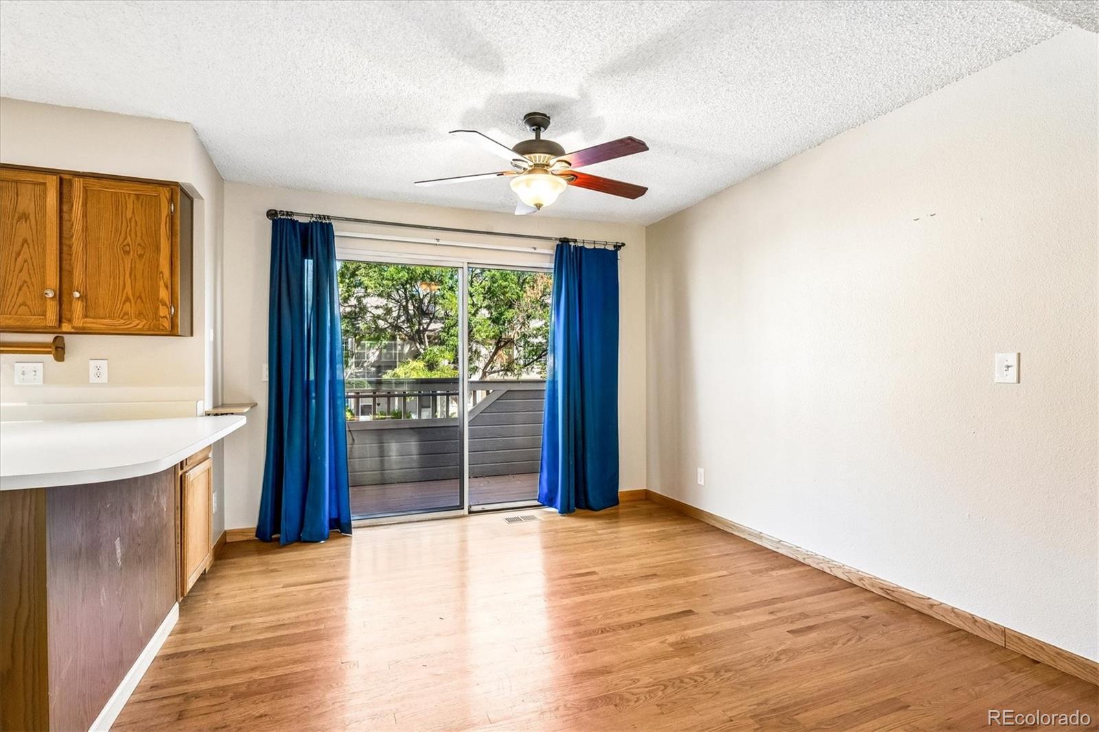 Unfurnished dining area with oak kitchen cabinets, blue curtains, and a sliding door to the balcony.