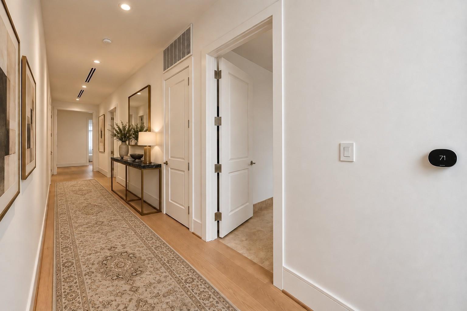 Furnished hallway with a patterned runner, framed artwork, and console table.