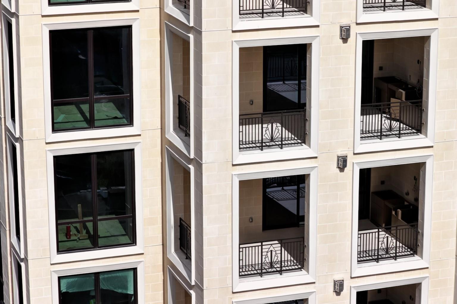 Residential building facade with recessed balconies and decorative black railings.