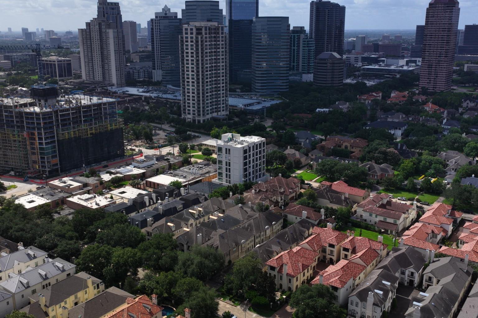 Aerial view of Houston homes and tree-lined streets, with the downtown skyline in the distance.