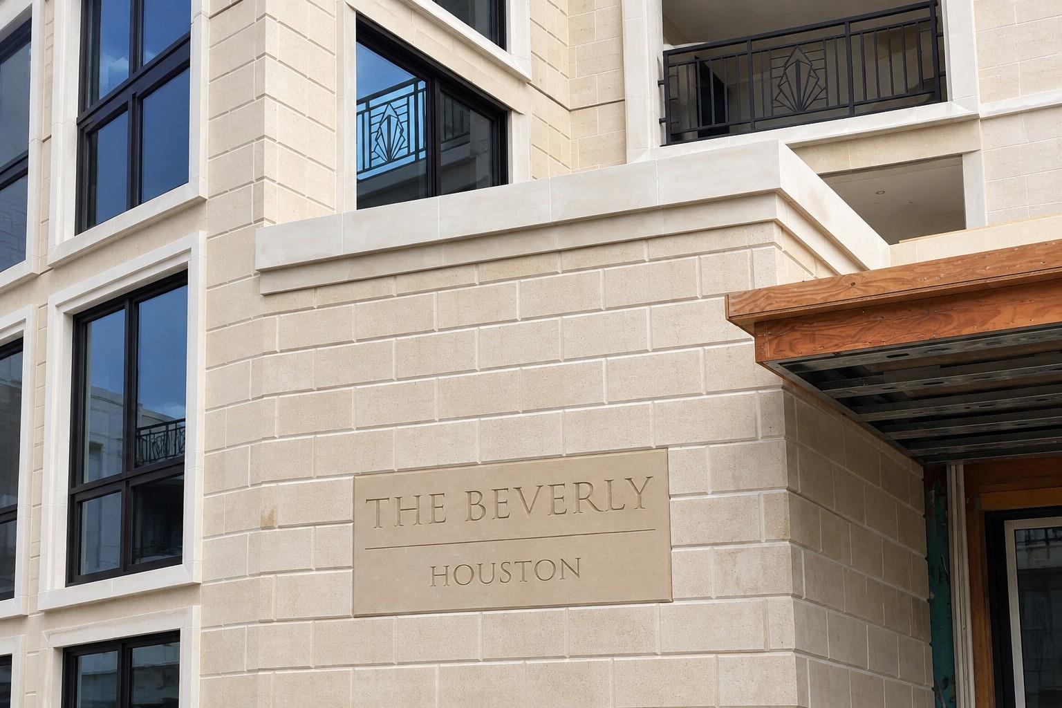 The Beverly Houston's stone-clad exterior with black-framed windows and decorative balcony railings.