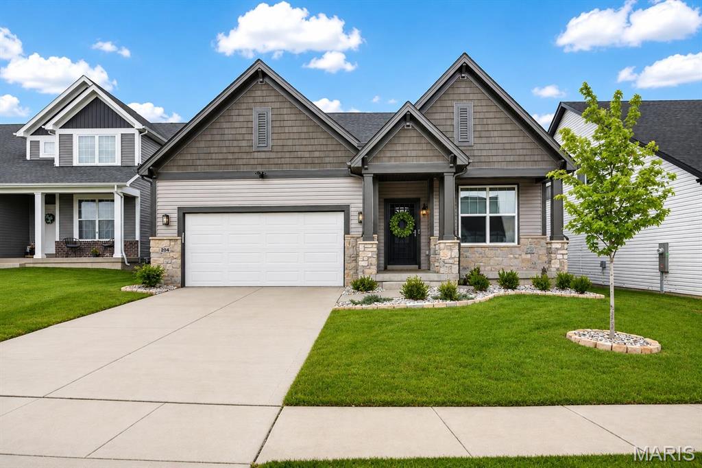 Gray gabled house with stone accents, a two-car garage, and a landscaped front lawn.