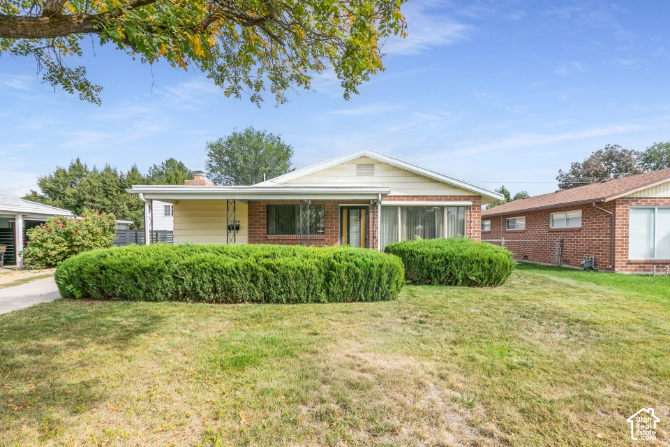 Single-story home with a brick facade, trimmed hedges, and a broad front lawn.