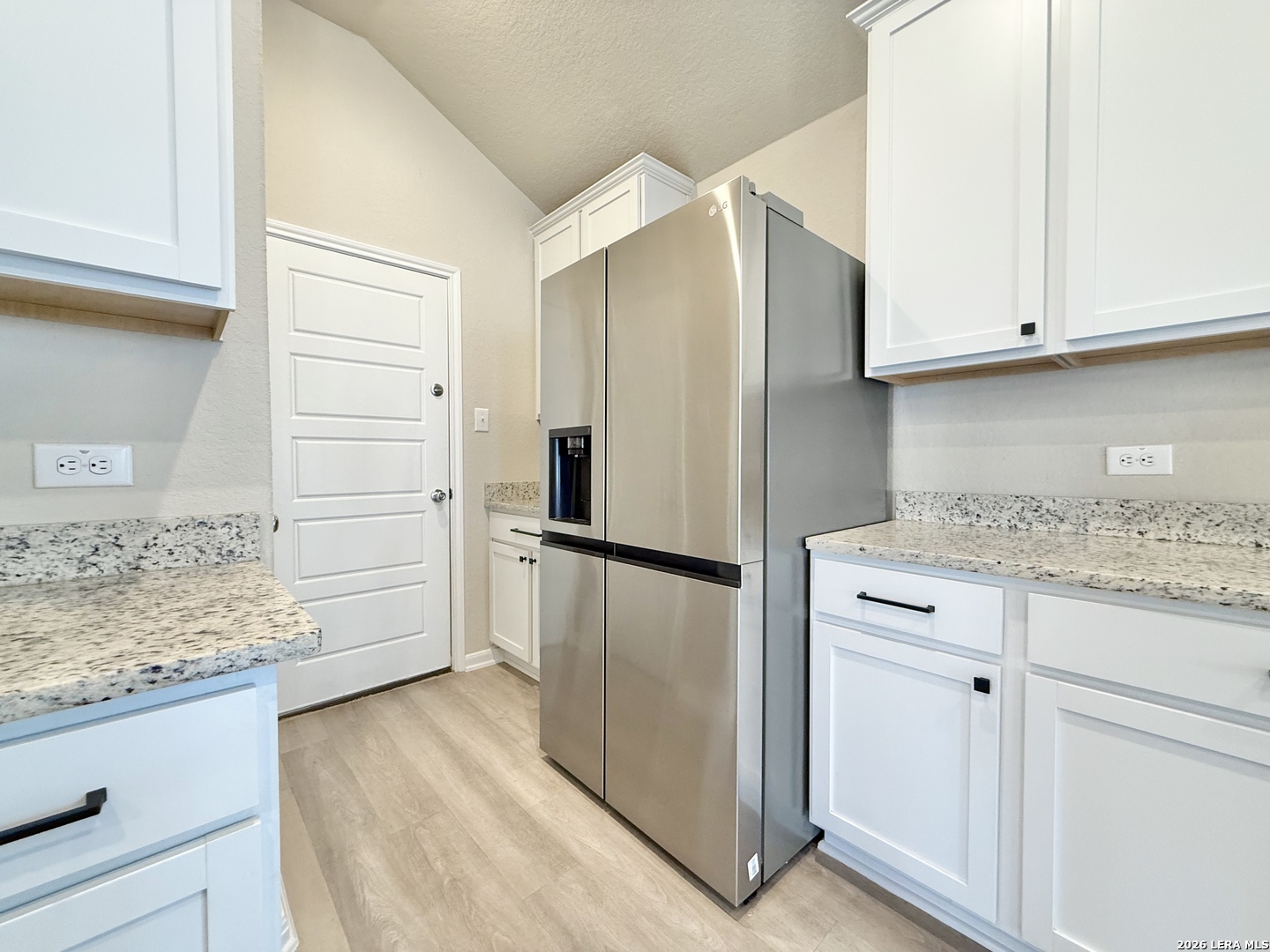 Kitchen with white cabinets, granite counters, and a stainless steel French-door refrigerator.