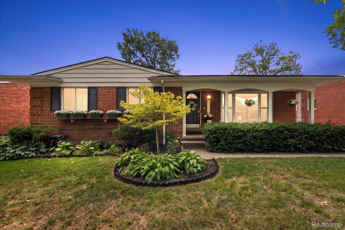 Single-story brick ranch home with a covered porch and landscaped front garden.