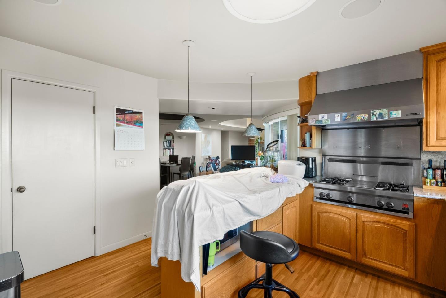 Kitchen with honey-colored cabinets, stainless steel range, and a cloth-covered central island.