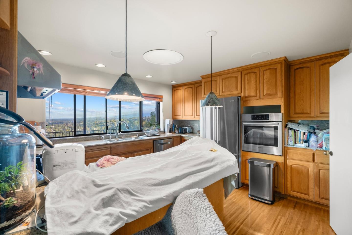 Kitchen with wood cabinets, stainless steel appliances, and a wide window overlooking the landscape.