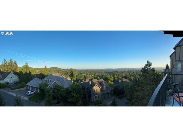 Panoramic view of homes and tree-covered hills from a balcony.