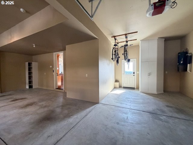 Garage with ceiling-mounted bicycles, white storage cabinets, and a concrete floor.