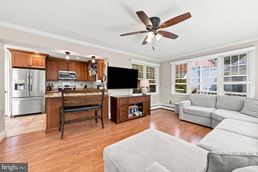 Open living room and kitchen with hardwood floors, wood cabinetry, and a gray sectional sofa.