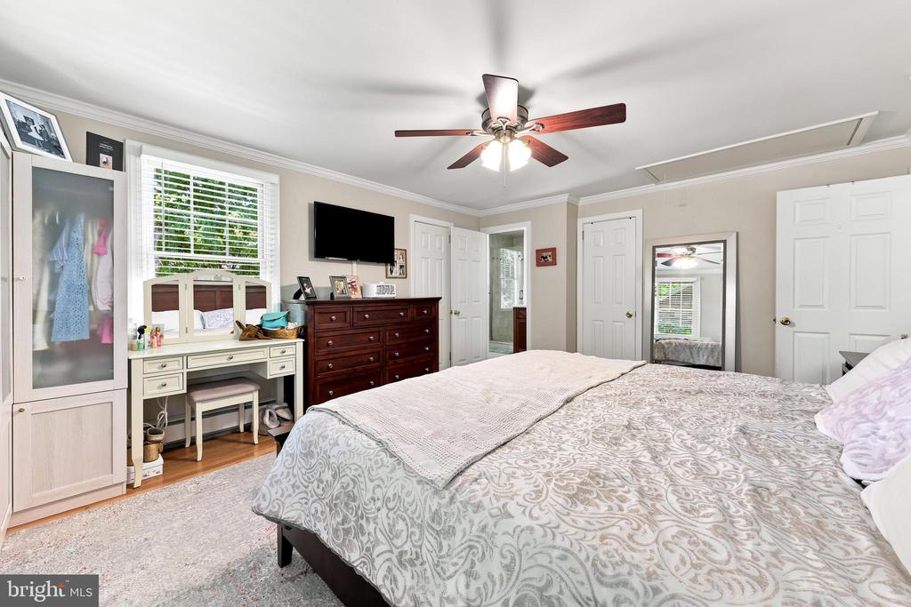 Bedroom with a patterned bed, built-in desk beneath a window, and dark wood dresser.