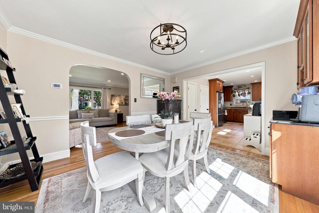 Dining room with a white table and chairs, opening to the living room and kitchen.