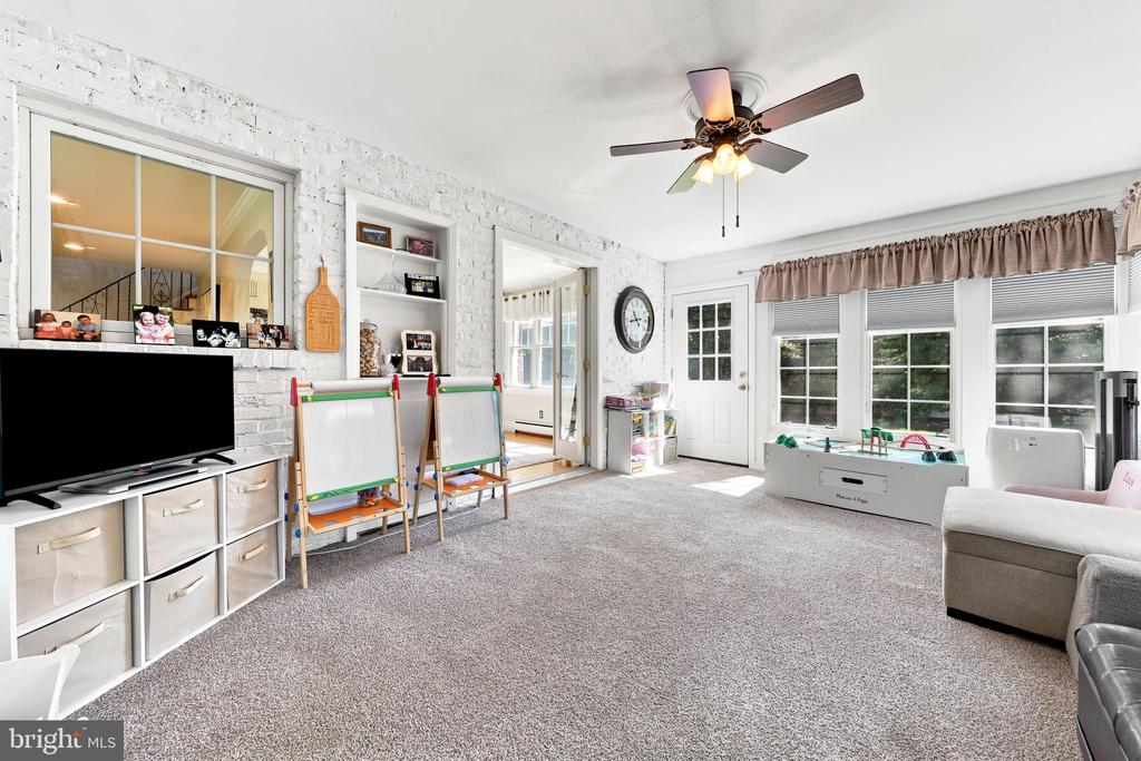 Playroom with white brick walls, large windows, children’s easels, and a gray sectional sofa.