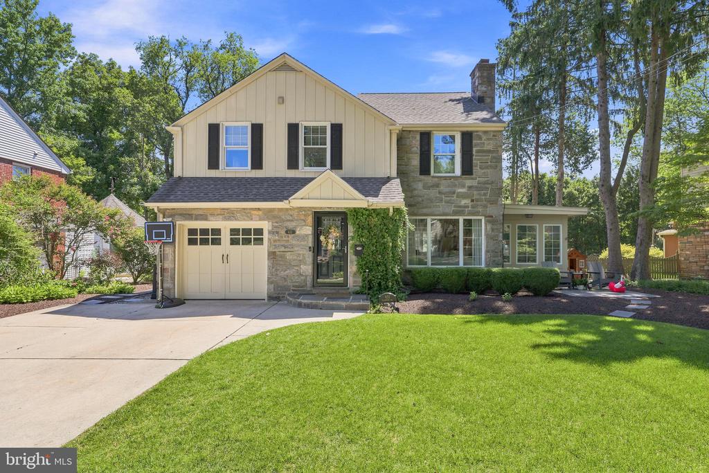 Two-story home with a stone facade, attached garage, broad driveway, and green lawn.