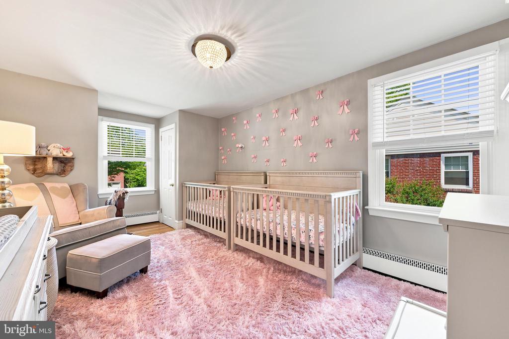 Nursery with a wooden crib, pink bow decorations, and a plush pink rug.