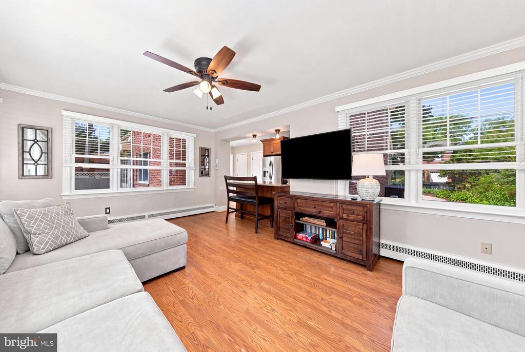 Living room with warm wood floors, a light sectional, large windows, and a wooden TV console.