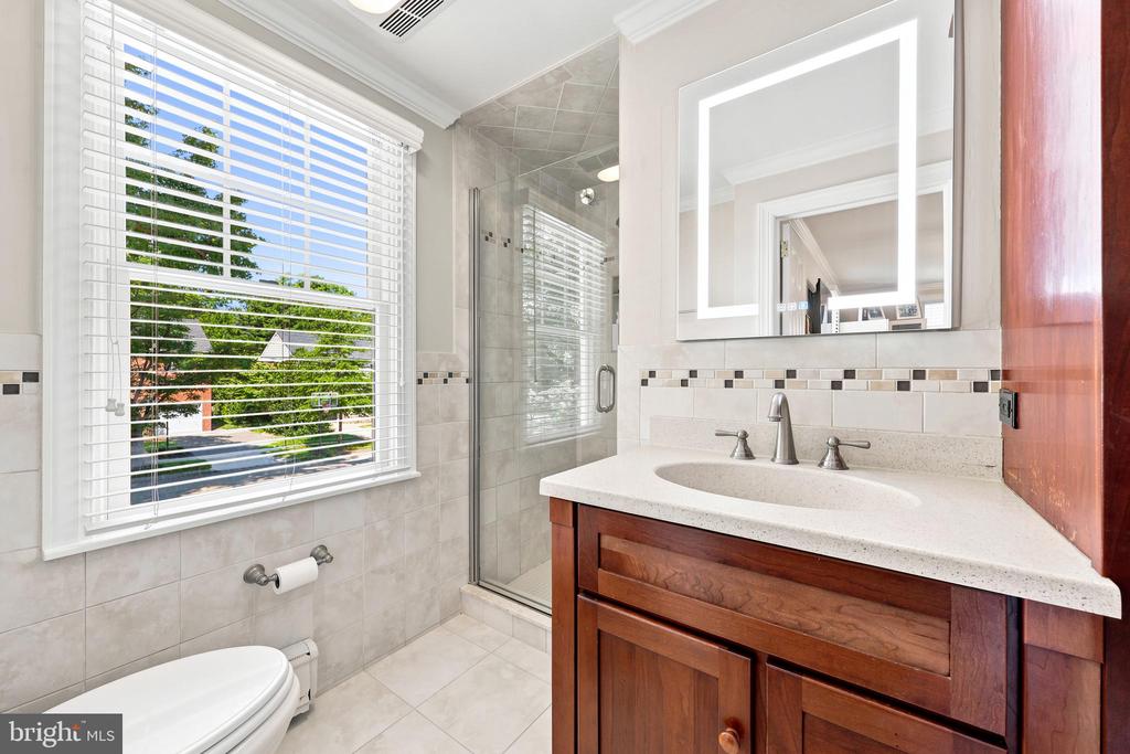 Bathroom with a glass shower, large window, and wooden vanity.