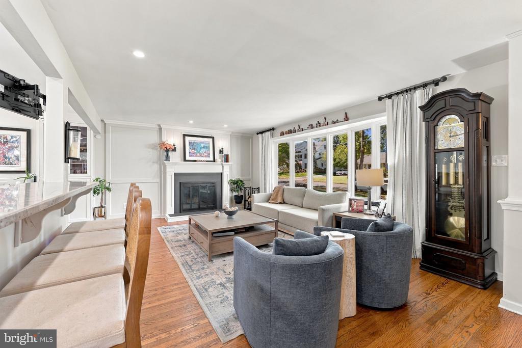 Living room with a white fireplace, large windows, gray seating, and hardwood floors.