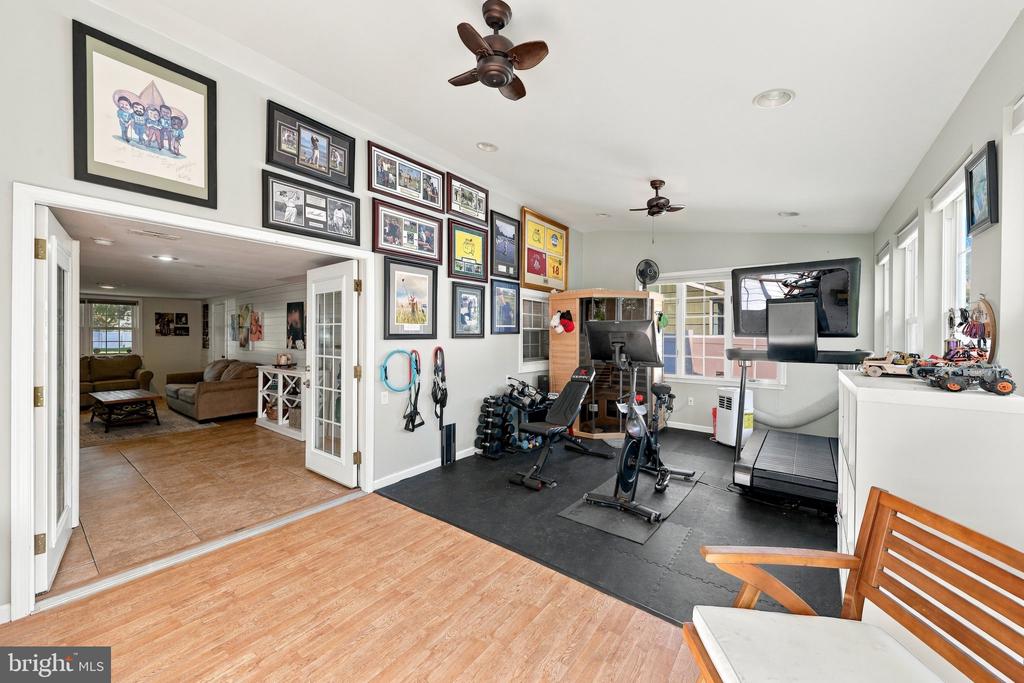 Home gym with exercise equipment and framed photos, opening into a living room.