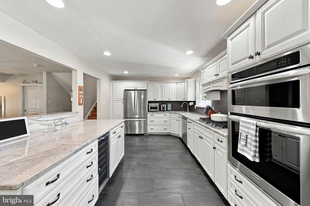 Kitchen with white cabinetry, stainless steel appliances, and gray tile flooring.
