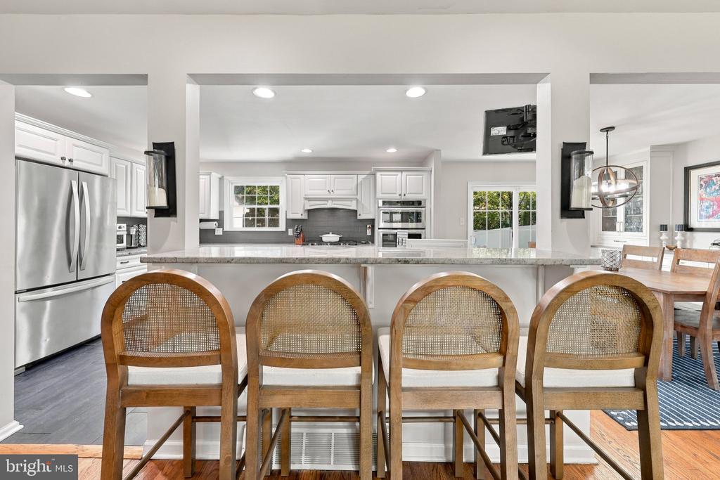 Kitchen with a large island and four cane-back stools, opening to a dining area.