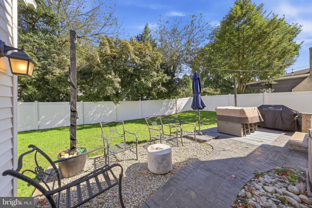 Backyard patio with stone paving, gravel seating area, outdoor furniture, and a covered grill.