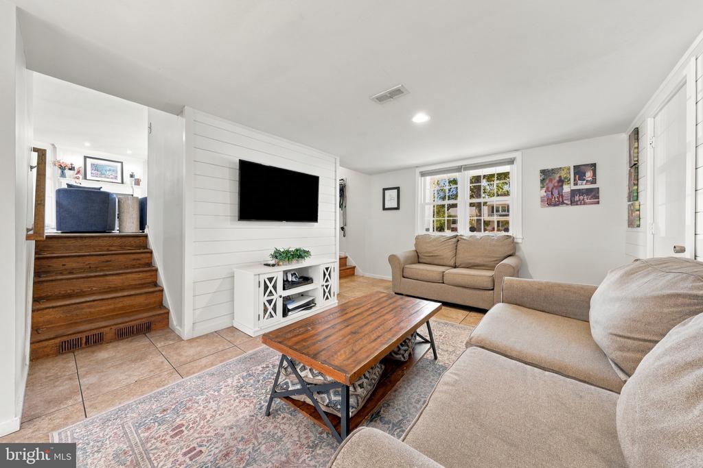Living room with a white shiplap TV wall, beige sofas, and a wooden coffee table.