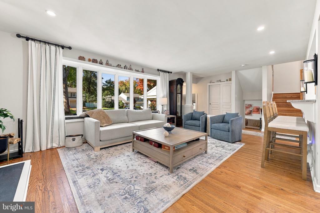 Living room with a white sofa, blue armchairs, and large windows overlooking the yard.