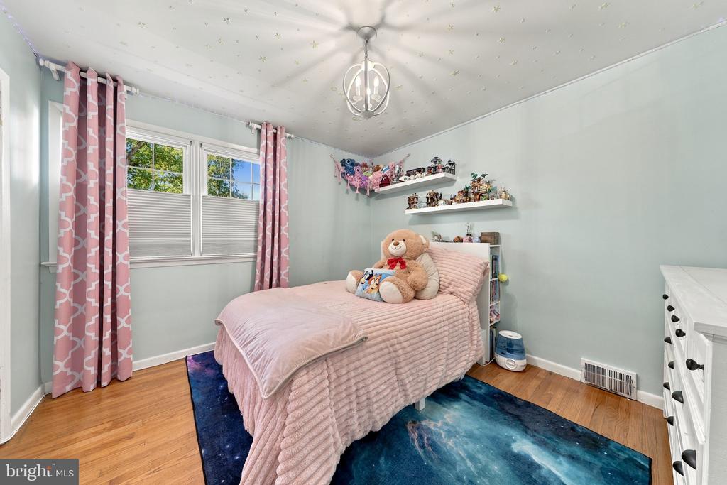 Bedroom with pink bedding, a teddy bear, and a blue area rug.