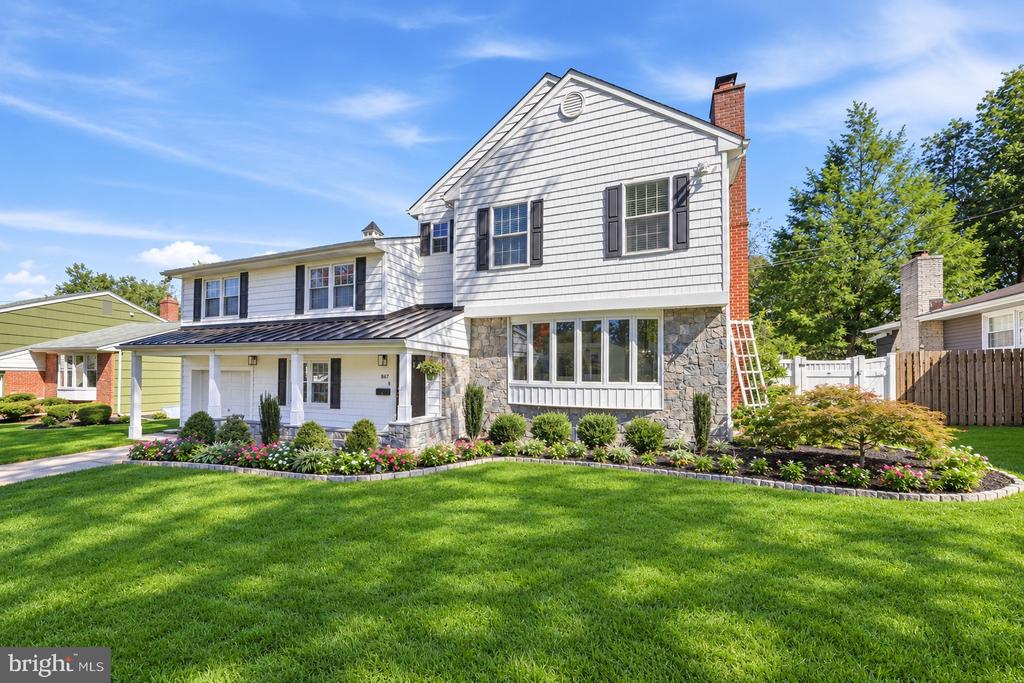 Two-story white-sided home with a stone facade, covered entry, and landscaped front lawn.