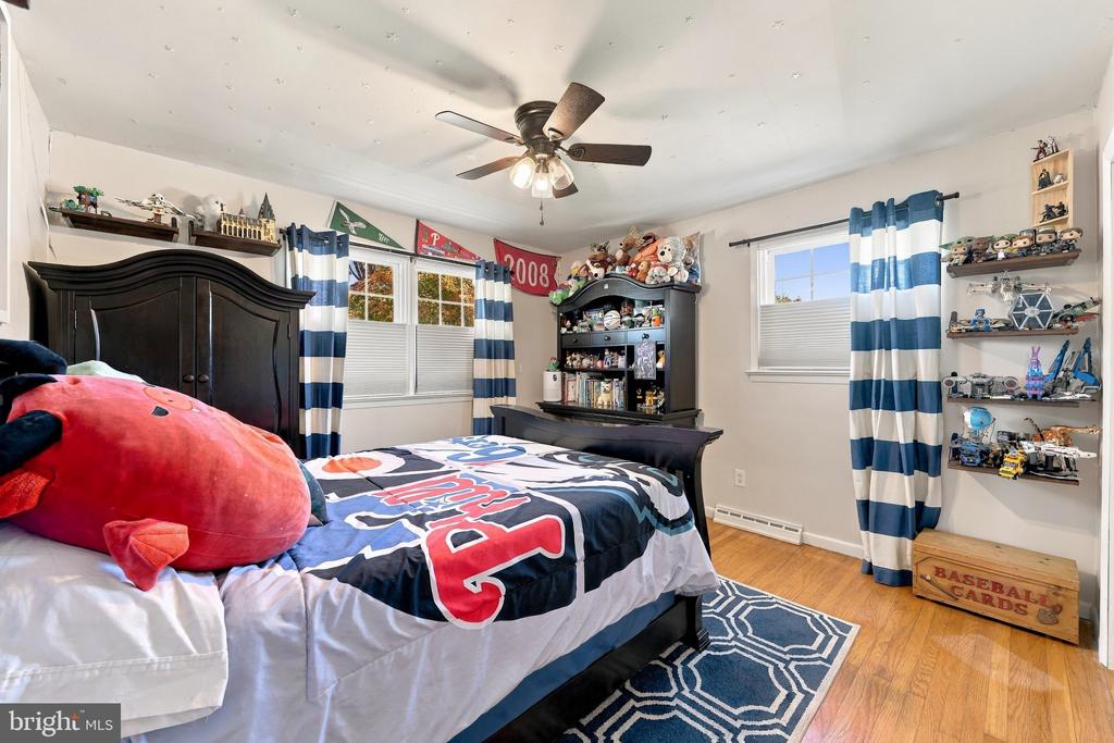 Bedroom with a baseball-themed bed, dark wood furniture, striped curtains, and shelves of collectibles.
