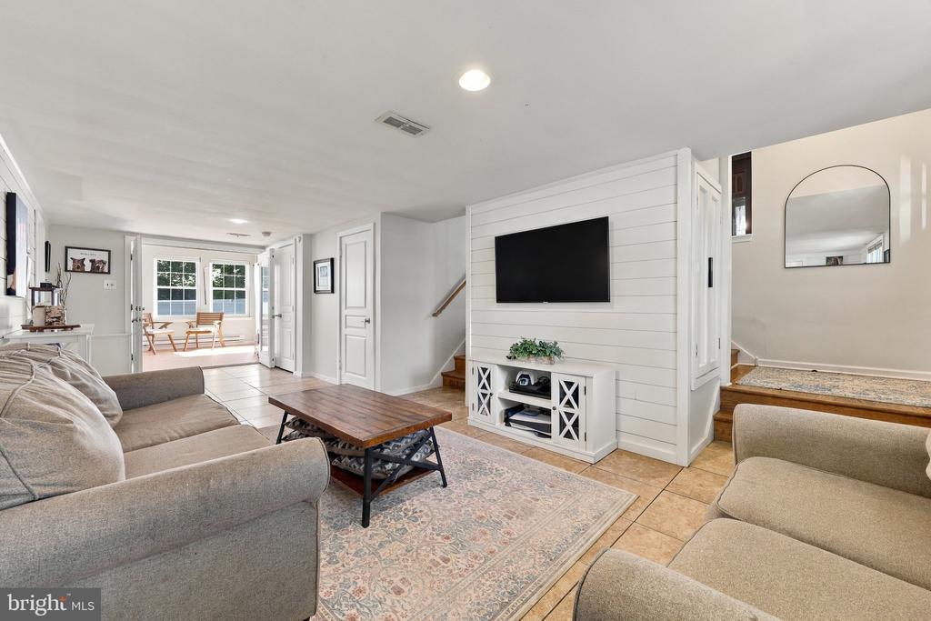 Living room with gray sofas, a wood coffee table, and a TV mounted on a white shiplap wall.