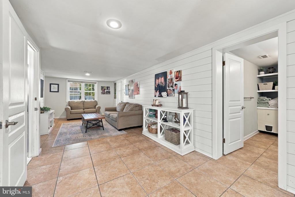 Living room with two sofas, a coffee table, and white shiplap walls beside a utility room.