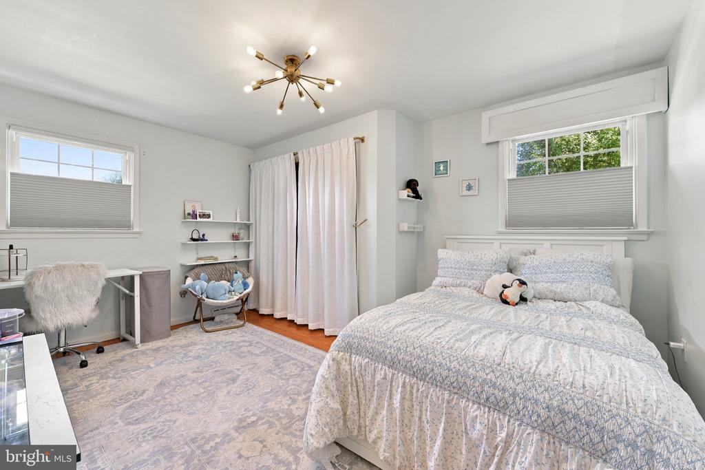Bedroom with a large patterned bed, two windows, and a small desk area.