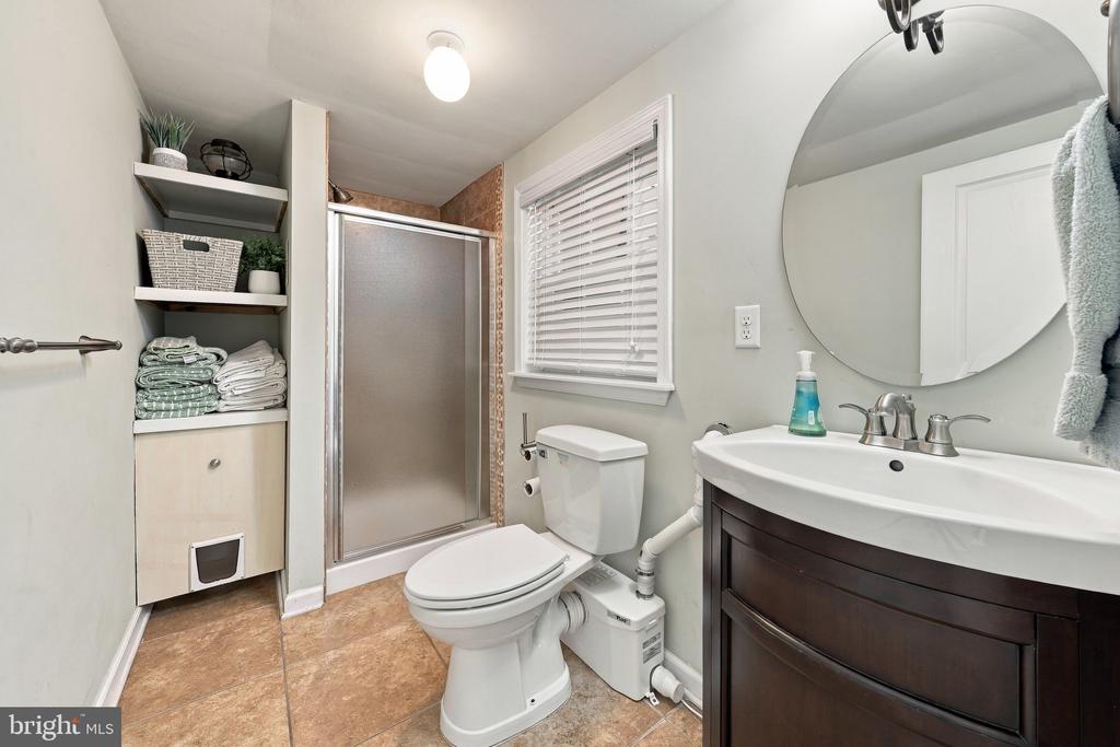 Bathroom with a glass shower, toilet, dark wood vanity, and built-in towel shelves.