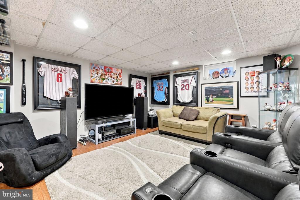 Finished media room with leather theater seats, a large television, and framed baseball memorabilia.