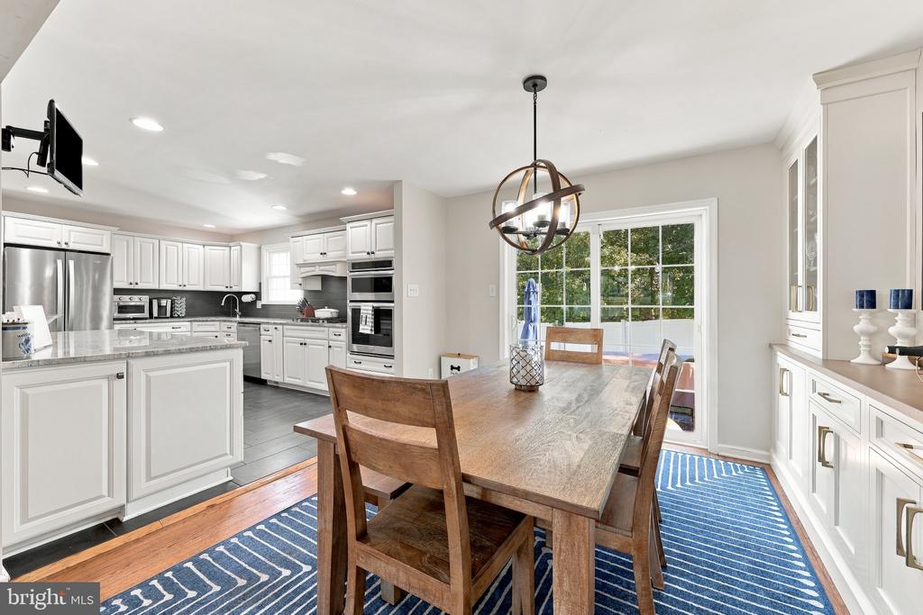 Dining area beside a white kitchen, with a wooden table and glass doors opening to the patio.