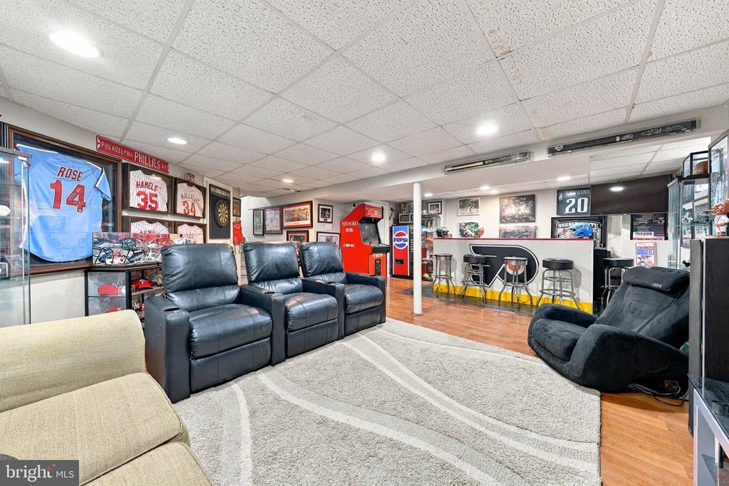 Sports-themed recreation room with leather recliners, Phillies memorabilia, and a counter with bar stools.