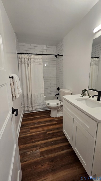 Bathroom with white vanity, tiled tub-shower, and dark wood-look flooring.