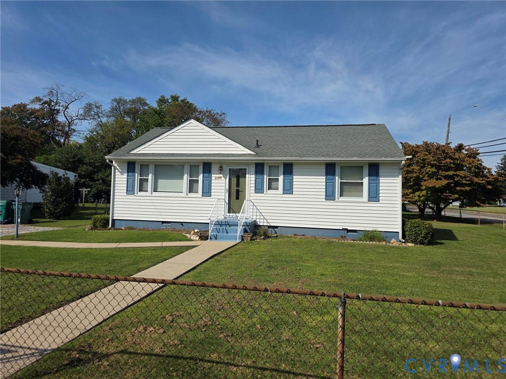 Single-story white house with blue shutters, front steps, and a lawn behind a chain-link fence.