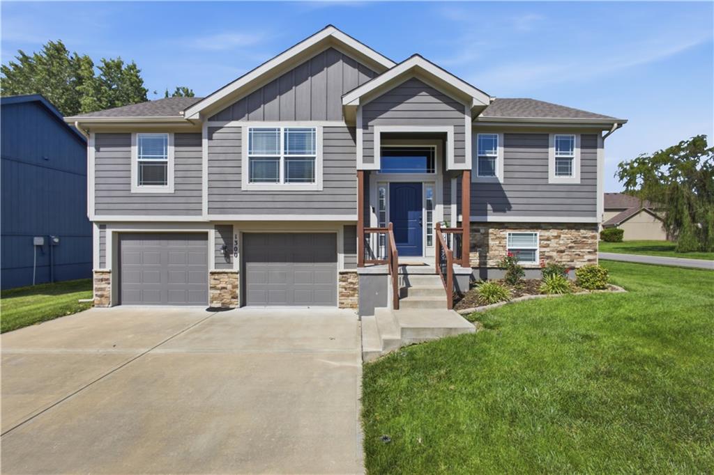 Gray two-story house with a blue front door, stone accents, and a two-car garage.