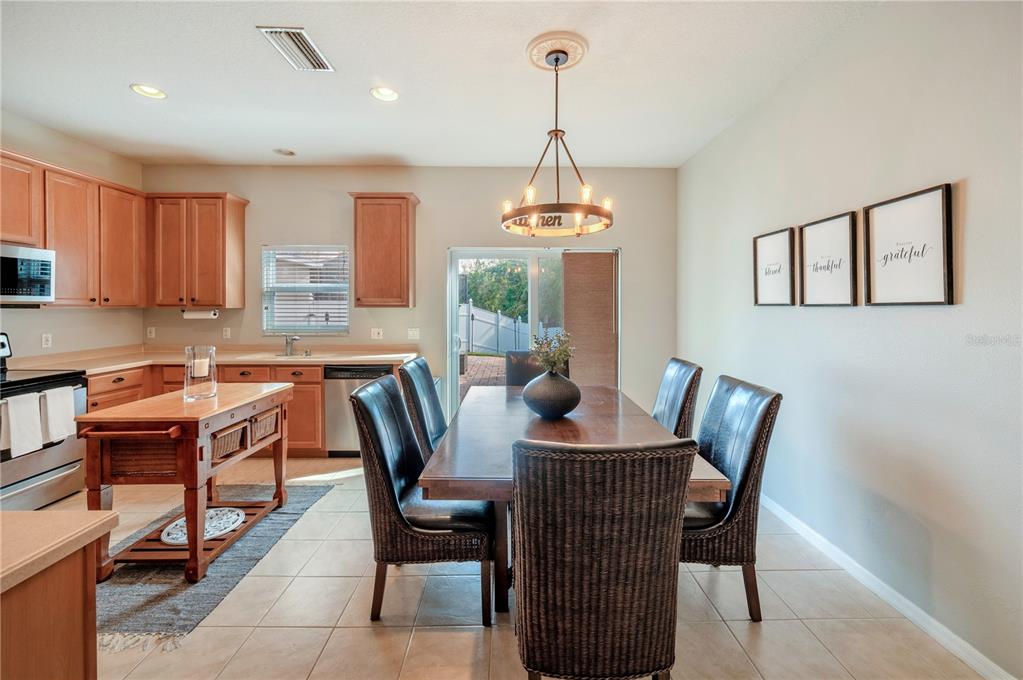 Kitchen and dining area with warm wood cabinets, a butcher-block island, and a table beside a patio door.