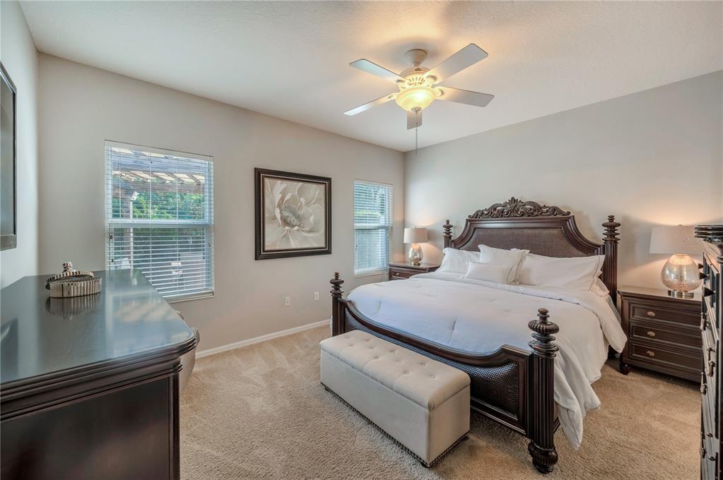 Bedroom with an ornate dark wood bed, white linens, matching nightstands, and a ceiling fan.