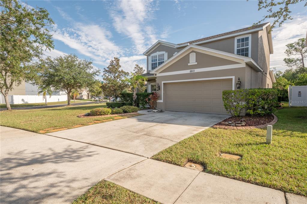 Two-story gray house with a double garage, wide driveway, and landscaped front lawn.