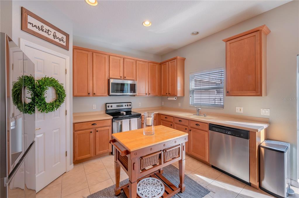 Kitchen with warm wood cabinets, stainless steel appliances, and a wooden island cart.