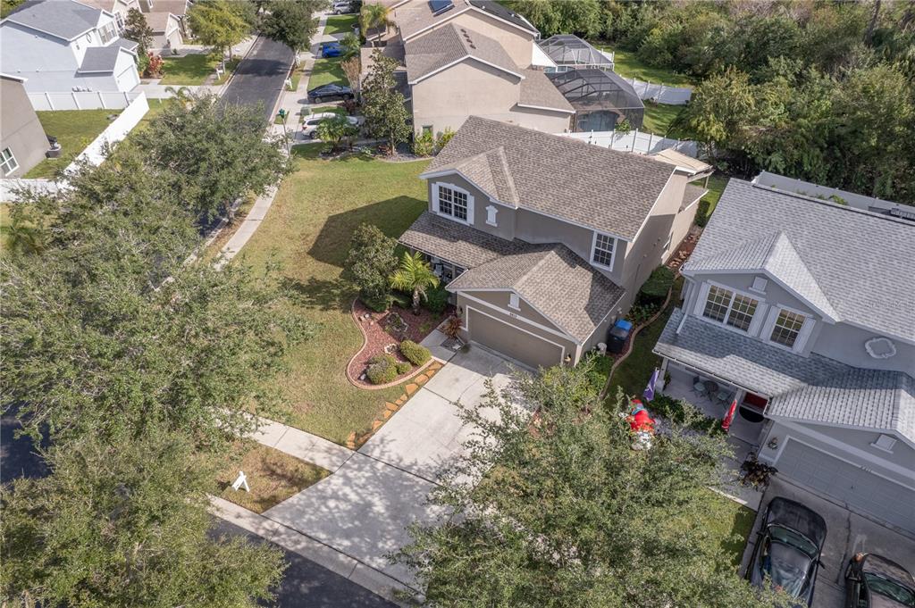 Aerial view of a two-story gray home with a front garage and landscaped yard.